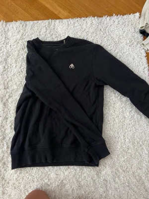 Svart sweatshirt  - En svart sweatshirt med rund hals och ribbade muddar. Från moose knuckles! Om ni vill ha fler bilder eller undra mågot så bara skriv!