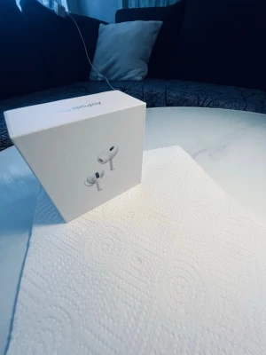 Apple AirPods Pro 2 trådlösa hörlurar - Säljer ett par Apple AirPods Pro med vit laddningsetui. Snygg och kompakt design med in-ear passform och brusreducering. Kommer i originalförpackning med tillbehör. Perfekta för musik, poddar och samtal.