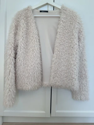 Ljusbeige fluffig teddyjacka - Supersoft och fluffig teddyjacka i ljusbeige från Gina Tricot. Jackan har lång ärm, öppen framtill och är gjord i ett mysigt, pälsliknande material. Perfekt för dig som vill ha en trendig och cozy look till hösten eller vintern.