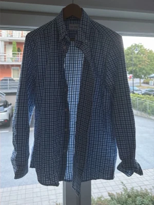 Blårutig långärmad skjorta - Snygg blårutig skjorta med klassisk krage och långa ärmar. Skjortan har knappar framtill och är tillverkad i ett mjukt bomullstyg som passar perfekt till jeans eller chinos. Perfekt för dig som gillar en avslappnad men ändå stilren look.