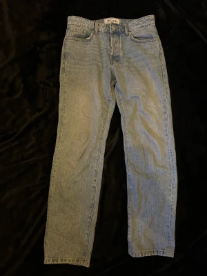 Blå raka jeans från Only & Sons - Snygga blå jeans från Only & Sons med klassisk rak passform och fem fickor. Jeansen har bälteshällor, knappgylf och är gjorda i ett slitstarkt denimtyg. Perfekta för en avslappnad och trendig look. Storlek: W30 L32