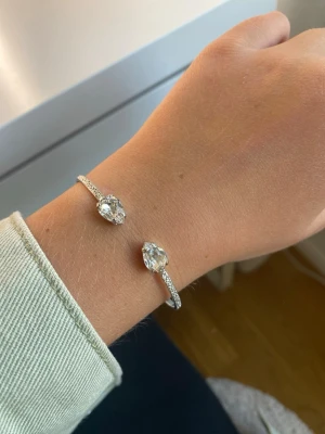 Silverfärgat armband med kristaller från Caroline Svedbom - Silver armband från Caroline Svedbom med två diamanter du kan justera armbandet beroende på hur du vill ha de och hur din arm är formad. 