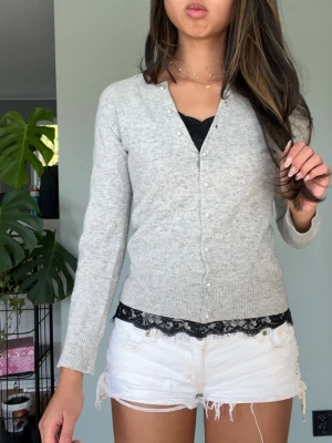 Ljusgrå cardigan med knappar - Lite urtvättat vilken märks på att passformen är lite sne. Står storlek m men skulle säga närmare xs eller s. 