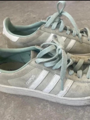 Adidas Campus ljusgröna sneakers stl 38 - Säljer ett par Adidas Campus sneakers i ljusgrönt mockamaterial med klassiska vita ränder på sidorna och matchande ljusgröna skosnören. Skorna har en låg profil och vit sula. Perfekta för dig som gillar retrostil och streetwear.
