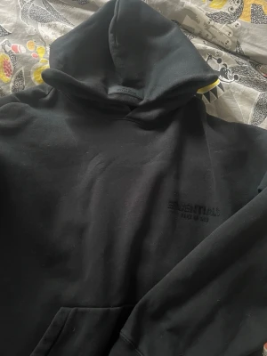 Svart Essentials hoodie - Säljer en svart hoodie från Essentials. Storleken är xs men är oversized så passar S-M