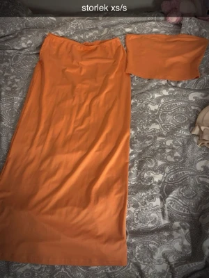 sett/ klänning - Säljer ett orange set med body och matchande bandeau-topp. Setet har en enkel, slät design och är tillverkat i ett mjukt, stretchigt material som sitter tajt mot kroppen. Perfekt för dig som gillar trendiga och färgstarka underkläder.