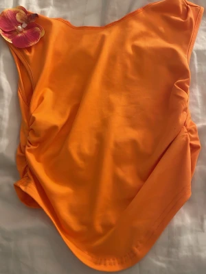 Orange baddräkt med rynkade sidor - Snygg orange baddräkt med rynkade detaljer på sidorna och klassisk skärning. Tillverkad i stretchigt material som passar perfekt för strand eller pool. Enkel och stilren design utan synligt märke.