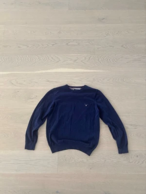 Mörkblå tröja från Gant - Snygg mörkblå tröja från Gant i stretchig bomull. Klassisk rund halsringning och diskret logga broderad på bröstet. Perfekt att matcha med jeans eller chinos för en clean look.