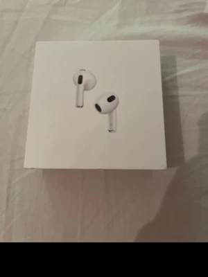 Apple airpods 3 2022 - Snygga trådlösa hörlurar från Apple i klassisk vit färg. AirPods levereras med ett smidigt laddningsetui som laddas via Lightning-kabel. Perfekta för musik, samtal och vardagsbruk. Modern design med rundade former och diskreta svarta detaljer.