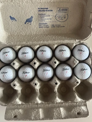 Golfbollar Titleist i äggkartong - Säljer ett set med tio vita golfbollar från Titleist, snyggt förvarade i en äggkartong. Perfekt för dig som vill fylla på golfutrustningen. Klassisk rund form och tydlig logga på varje boll.
