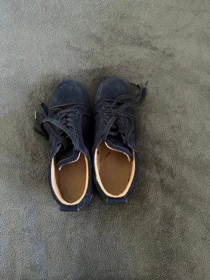 Mörkblå sneakers i mocka - Snygga mörkblå sneakers i mocka med svart sula och matchande mörkblå skosnören. Skorna har en låg profil och klassisk design som passar till många olika stilar. Insidan är ljusbeige och materialet ger en soft och stilren vibe. Ingen sko box