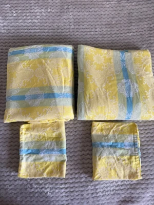 Påslakan 2st + örngott 2st - Ett bäddset i bomull med gula, blå och vita ränder samt dekorativa blommönster. Setet innehåller två påslakan och två örngott. Mjukt tyg med klassiskt retroinspirerat mönster, perfekt för att liva upp sovrummet. Fina och fräscha  Mått 190*125. 