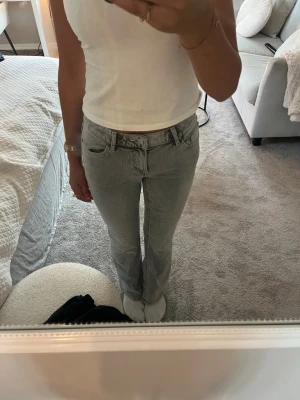 Grå raka jeans med hög midja - Säljer ett par grå jeans med rak passform och hög midja. Jeansen har klassiska fem fickor, bälteshällor och dragkedjegylf. Materialet är denim i en ljusgrå tvätt som ger en avslappnad vibe. Perfekta till en enkel topp eller hoodie.