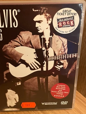 Elvis '56 DVD-dokumentär - DVD-dokumentär om Elvis Presley med svartvit omslagsbild. Innehåller sällsynta tidiga inspelningar och aldrig tidigare visat material från 1956. Omslaget har klassisk retrostil och listar låtar som Blue Suede Shoes och Hound Dog. Perfekt för Elvis-fans och samlare.