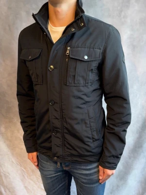 J-Lindeberg Bailey Fieldjacket Svart - Stl S - Riktigt snygg Höst/vår Fieldjacket från J-Lindeberg i färgen svart! | Mycket bra skick: 9/10 | Stl: S, modellen är 178cm och väger 78kg, passar bra mellan 174-185cm 🙌  | Hör av dig vid frågor // Galgen 🫡 Har fler Jackor i profilen samt om du köper mer plagg blir de billigare!