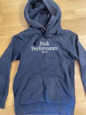 Mörkblå loungewear-set Peak Performance - Mysigt mörkblått loungewear-set från Peak Performance med hoodie och matchande byxor. Hoodien har magficka, dragsko och logga framtill. Byxorna har resårmidja med snörning, fickor och logga på benet. Perfekt för chill dagar hemma.