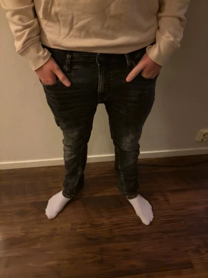 Svarta slim fit jeans med tvättade detaljer - Säljer ett par svarta slim fit jeans med snygga tvättade detaljer och slitningar. Jeansen har klassisk femficksmodell, normal midja och smal passform hela vägen ner. Perfekta för dig som gillar en modern och avslappnad stil.