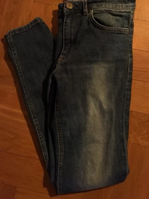 Mörkblå slim fit jeans - Snygga mörkblå slim fit jeans med klassisk femficksdesign och lätt slitna detaljer framtill. Jeansen har normal midja och stängs med knapp och dragkedja. Perfekta för en avslappnad och trendig look.