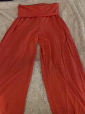 Vida orange leggings från 157 - Vida leggings i en snygg orange färg från 157. De har låg midja med bred linning och är tillverkade i ett mjukt, stretchigt material som känns skönt mot huden. Perfekta för dig som gillar en avslappnad och trendig stil.