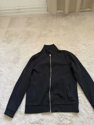 Svart zip tröja  - En stilren svart tröja med hel dragkedja framtill och hög krage. Pris kan diskuteras.