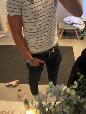 Vit randig t-shirt från Lyle & Scott - Vit t-shirt från Lyle & Scott med tunna blå ränder och klassisk gul logga på bröstet. T-shirten har rund halsringning med blå kant och korta ärmar. Storlek S 