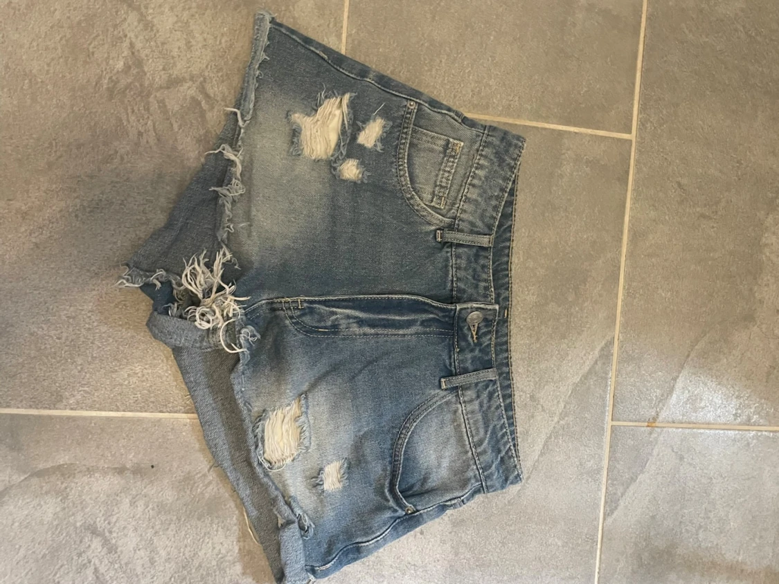 Blå slitna jeansshorts