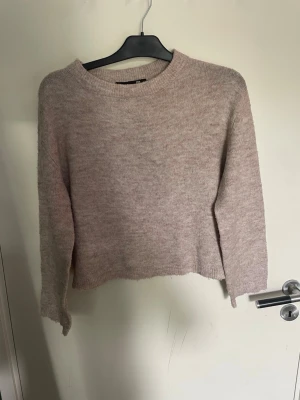 Beige stickad tröja från 157 - Mysig beige stickad tröja från 157 i storlek XS. Tröjan har en rund halsringning, långa ärmar och är tillverkad i ett mjukt, fluffigt material. Perfekt för lager på lager och enkel att matcha med olika outfits. Har ett litet hål på vänster axel
