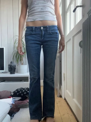 Mörkblå bootcut jeans med fickdetalj - Snygga mörkblå bootcut jeans med markerade sömmar och cool fickdetalj bak. Klassisk femficksmodell och låg midja. Jeansen har en lätt utsvängd passform och är perfekta till en avslappnad stil.
