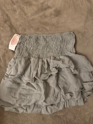 Grön volangkjol  - Supersöt grön kjol med volanger och bred smockresår i midjan. Kjolen har en luftig och lätt struktur som ger en avslappnad men ändå trendig look. Perfekt att matcha med en enkel topp för en cool outfit.