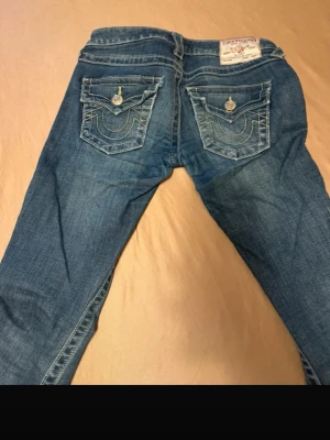 True religion jeans  - Säljer ett par blå jeans från True Religion med snygga broderade bakfickor och dekorativa knappar. Dom är flare. 