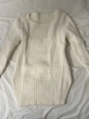 Vit ribbstickad tröja - Säljer en långärmad, vit ribbstickad tröja med rund halsringning. Tröjan har en kroppsnära passform och är gjord i ett mjukt, stretchigt material som känns skönt mot huden. 