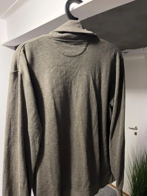 Olivgrön kofta från Polo Ralph Lauren - Snygg olivgrön kofta från Polo Ralph Lauren med sjalkrage, knäppning framtill och två fickor. Tillverkad i mjukt material och har en diskret logga broderad på bröstet. Perfekt för lager på lager och en avslappnad stil.