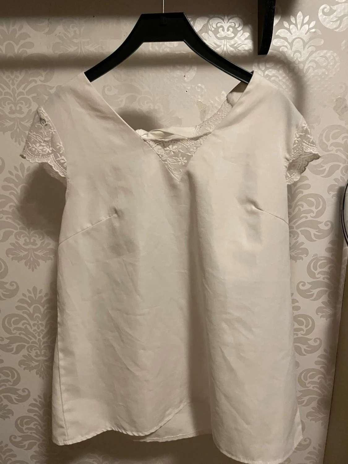 Vit blus med spetsdetaljer och rosett
