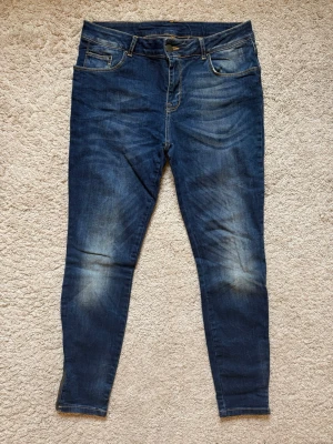 Mörkblå skinny jeans med dragkedja (NYA!) - Helt nya och oanvända! Säljer ett par mörkblå skinny jeans med snygga slitningar och dragkedjor vid bensluten. Jeansen har klassisk femficksdesign och gul kontrastsöm. Superfina och trendar nu i höst.