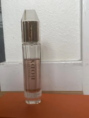 Burberry Body Eau de Parfum - Burberry Body Eau de Parfum i en elegant, transparent glasflaska med guldtonad kork och detaljer. Flaskan har en modern, avlång och multifasetterad form med subtilt rosa doftvätska inuti. Perfekt för dig som gillar lyxiga och klassiska parfymer.