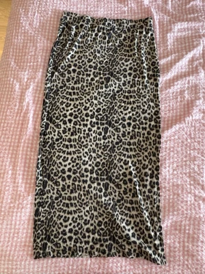 Leopardmönstrad långkjol Lager 157 - Säljer en långkjol från Lager 157 The Black Label Collection  i storlek XS. Kjolen har ett snyggt leopardmönster i beige och svart, rak passform och resår i midjan. Perfekt för dig som vill sticka ut med ett djurmönstrat plagg.