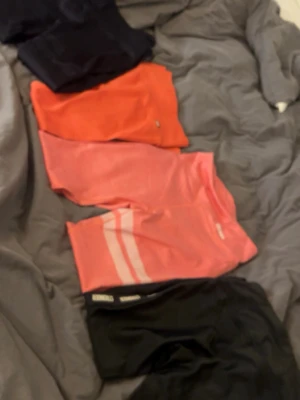 Fyra par tränings tajts från stronger - Fyra par tränings tajts i olika färger: ett par svarta ribbade, ett par orange, ett par rosa/coral med vita ränder och ett par helsvarta ribbade med stronger text på sidorna. Super fina och sköna men andvänder inte då jag inte tränar ofta💕💕