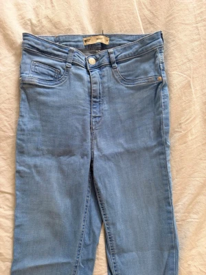 Ljusblå skinny jeans med hög midja - Säljer ett par ljusblå skinny jeans med hög midja och klassisk femficksmodell. Jeansen har smal passform och är tillverkade i stretchigt denimtyg för extra komfort. Perfekta till knähöga stövlar✨