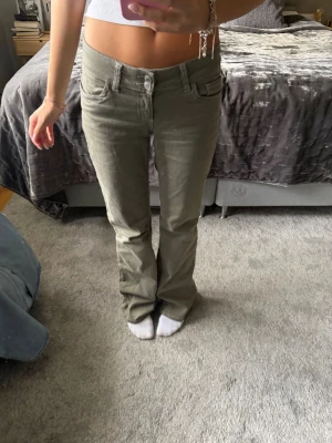  bootcutjeans från Nelly! - Snygga olivgröna jeans med bootcut-passform och klassiska fickor fram och bak. Byxorna har låg midja och stängs med knapp och dragkedja. Perfekta för en avslappnad och trendig stil. Har inga defekter, kom för fler bilder. 