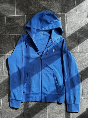 Ralph Lauren Zip Hoodie - Tja! Säljer nu min ljusblåa zip hoodie från Ralph Lauren. Storleken är S och skicket är mycket bra! Köpte för något år sedan på Boost men använder inte plagget så mycket längre. Nypris ligger på över 2000kr! Vid frågor eller funderingar är det bara att höra av sig! Kvitto för att bevisa äktighet finns!