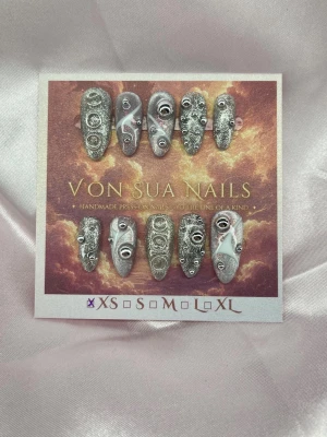 Rivet (XS);Medium Almond - Handgjorda press-on nails i Medium Almond med silverglittrig bas, metalliska nitar, ringdetaljer och vita 3D-accenter. Varje nagel har sin egen design för ett futuristiskt, industriellt uttryck.  Storlek: XS Form: Medium Almond 10 handgjorda naglar Prep-kit medföljer.
