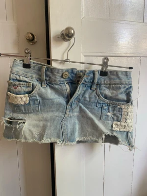 Ljusblå jeanskjol från Hollister - Ljusblå lågmidjad jeanskjol från Hollister med slitningar 