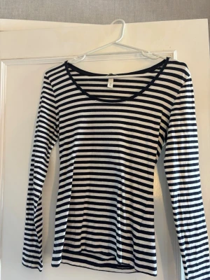 Randig långärmad topp i bomull - Snygg långärmad topp med svartvita horisontella ränder och rundad halsringning. Tillverkad i mjuk bomull som känns skön mot huden. Perfekt att styla med jeans eller kjol för en enkel och clean look.