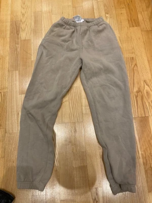 Beige mjukisbyxor med resår - Säljer ett par beige mjukisbyxor med resår i midjan och vid bensluten. Byxorna har en enkel och avslappnad passform, perfekta för chill dagar. Tillverkade i mjukt material som känns skönt mot huden.