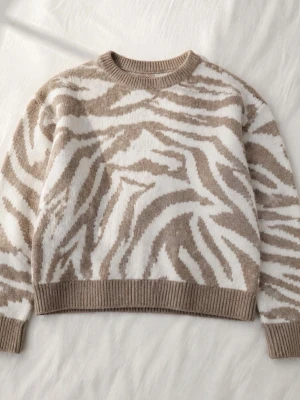 Beige och vit zebramönstrad stickad tröja - Säljer en supermjuk stickad tröja med beige och vitt zebramönster. Tröjan har rund hals, ribbade muddar och avslut. Perfekt för dig som gillar djurmönster och vill ha något både trendigt och bekvämt i garderoben.Den ser lägre ut en va den är på första bilden