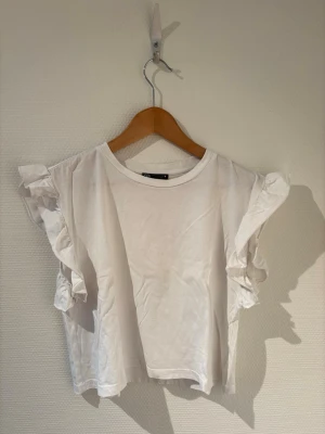 Zara topp med volanger  - Vit topp med volanger vid armarna från Zara🤍.        Storlek S