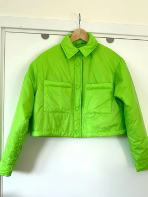 ONLY grön / neongrön jacka - storlek M - Stilren kort jacka i en livlig grön / neongrön färg från ONLY i storlek M. Tidlös modell med klassisk krage och knäppning framtill. Jackan har två bröstfickor med lock och knappar, samt långa ärmar med muddar. Den korta passformen gör den till ett mångsidigt plagg som kan stylas på många sätt. Nypris 799:-. Mycket gott skick, som ny!