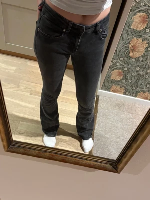 Svarta bootcut jeans med låg midja - Säljer ett par svarta bootcut jeans med låg midja och klassisk femficksmodell. Jeansen har en lätt tvättad look och raka ben som går ut lite nedtill. Perfekta till en avslappnad stil och passar till det mesta.