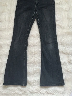 Svarta bootcut jeans - Snygga svarta bootcut jeans från Gina Tricot med klassisk femficksmodell. Jeansen har en mörk tvätt och kontrastsömmar på bakfickorna som liknar de från Nelly. Använda men fint skick! 
