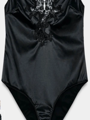 Svart satinbody med spets - Svart body i satinliknande material med dekorativ spets framtill. Kroppsnära passform och ärmlös design som ger en elegant och trendig look. Perfekt att styla med höga byxor eller kjol för en chic outfit.
